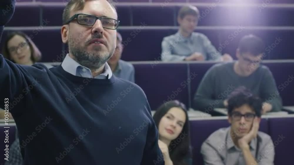 College professor is teaching a class of multi-ethnic students while pointing the desk with a marker. Shot on RED Cinema Camera. College professor is teaching a class of multi-ethnic students while pointing the desk with a marker. Shot on RED Cinema Camera.