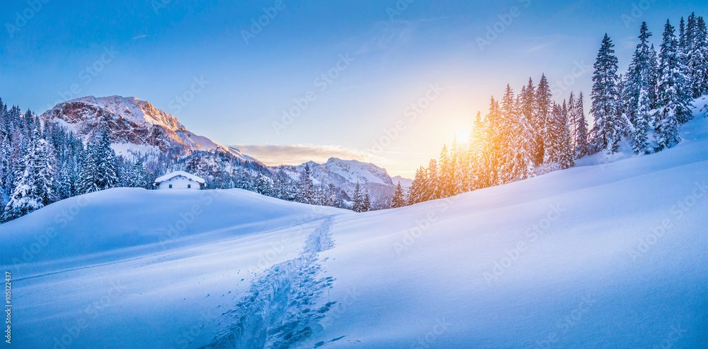 Winter wonderland in the Alps with mountain chalet at sunset