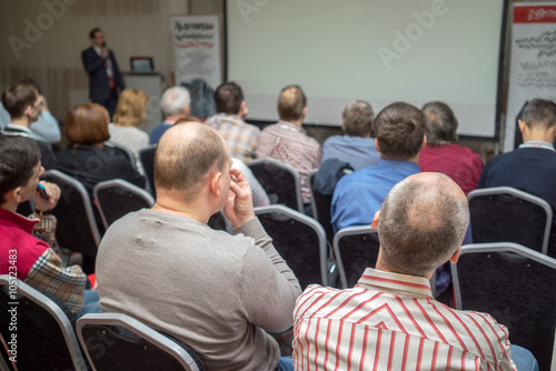 Person delivering a speech. Audience at a conference presentation.
