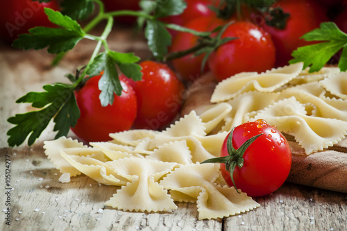 Italian dry pasta farfalle in the form of bows with cherry tomat photo