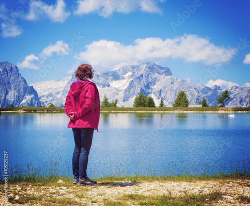 woman standing beside a clear mountain lake enjoying the view