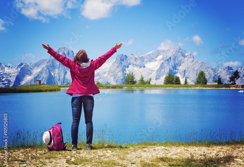 woman with arms wide open standing beside a clear mountain lake photo