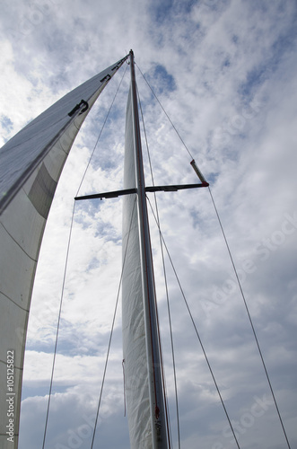 White sail of a sailing yacht against the sky seen from below