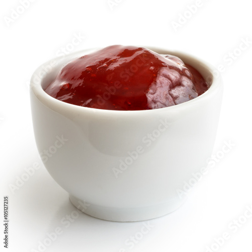 Small white ramekin of red strawberry jam isolated on white. In