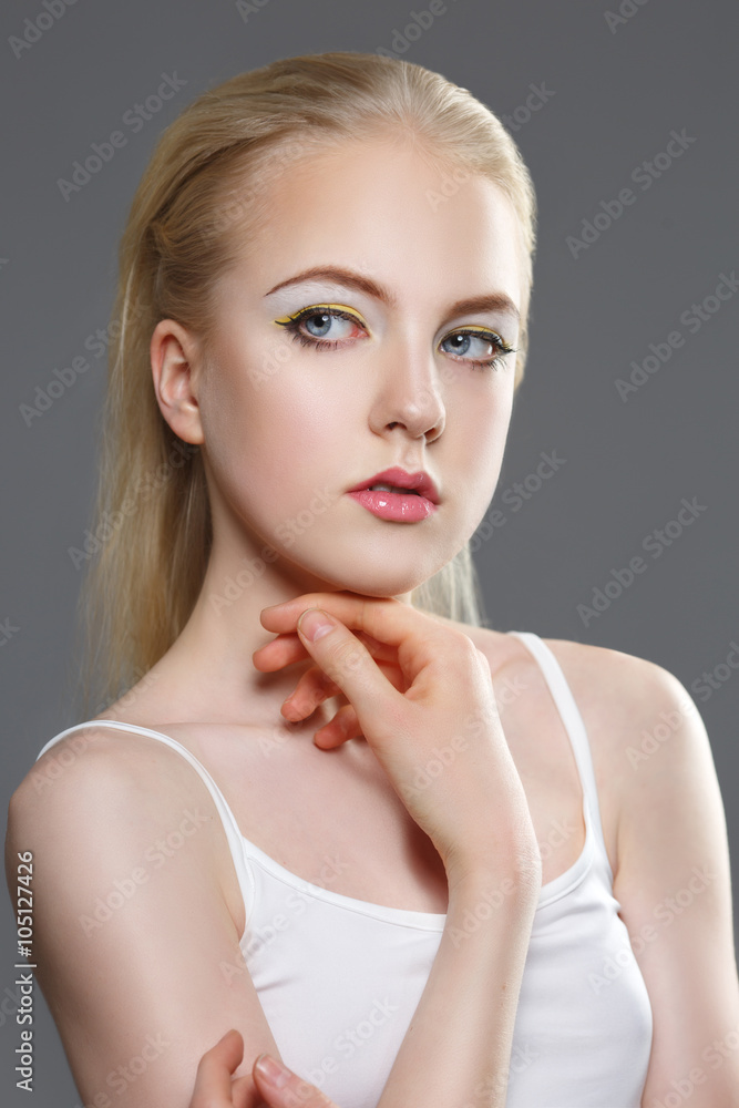 Fototapeta premium beauty portrait of a young blonde woman with make-up on a gray background