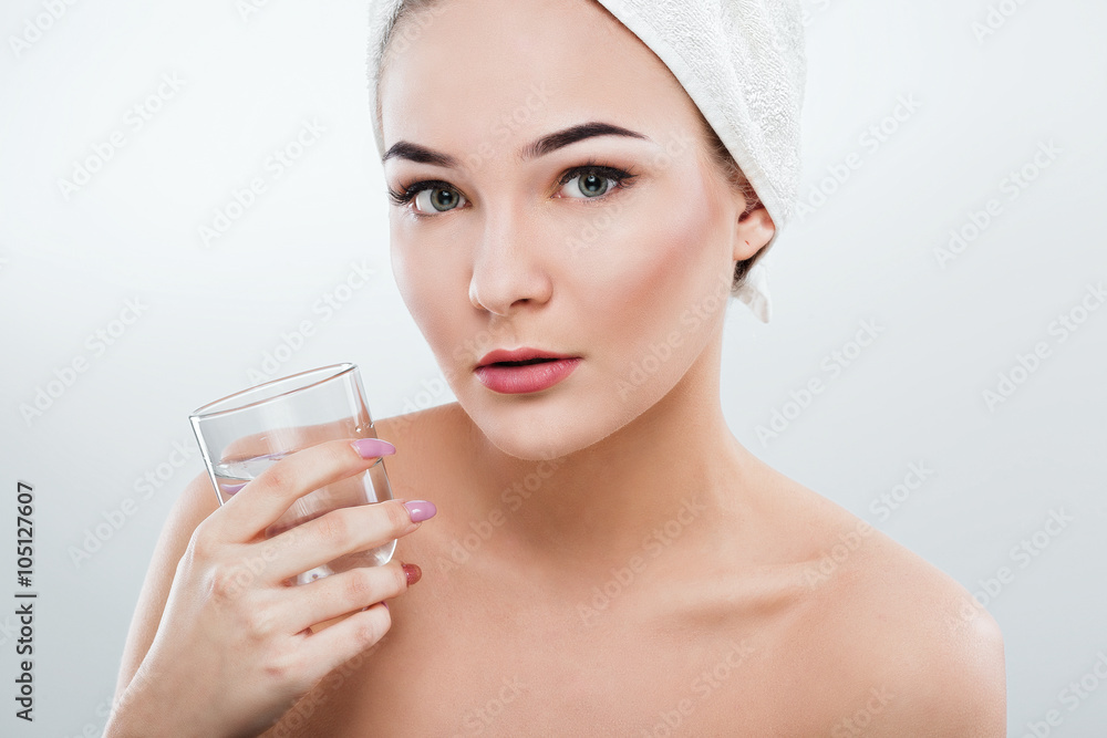 Girl with naked shoulders and white towel holding glass of water Girl with naked shoulders and white towel holding glass of water