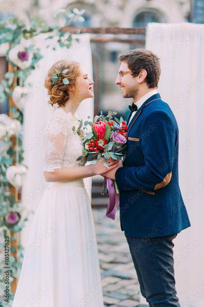 Charming wedding couple lovingly looking on each other on the wedding ceremony Charming wedding couple lovingly looking on each other on the wedding ceremony