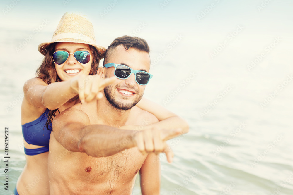 Obraz premium Happy couple pointing at the beach