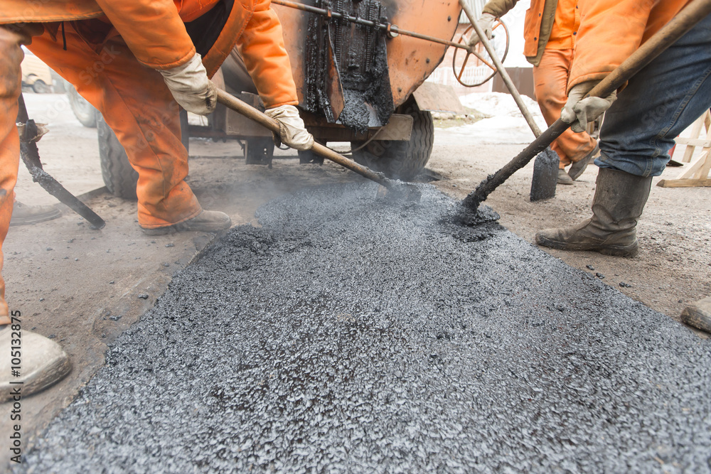 Road workers laid asphalt, repairing the road Road workers laid asphalt, repairing the road