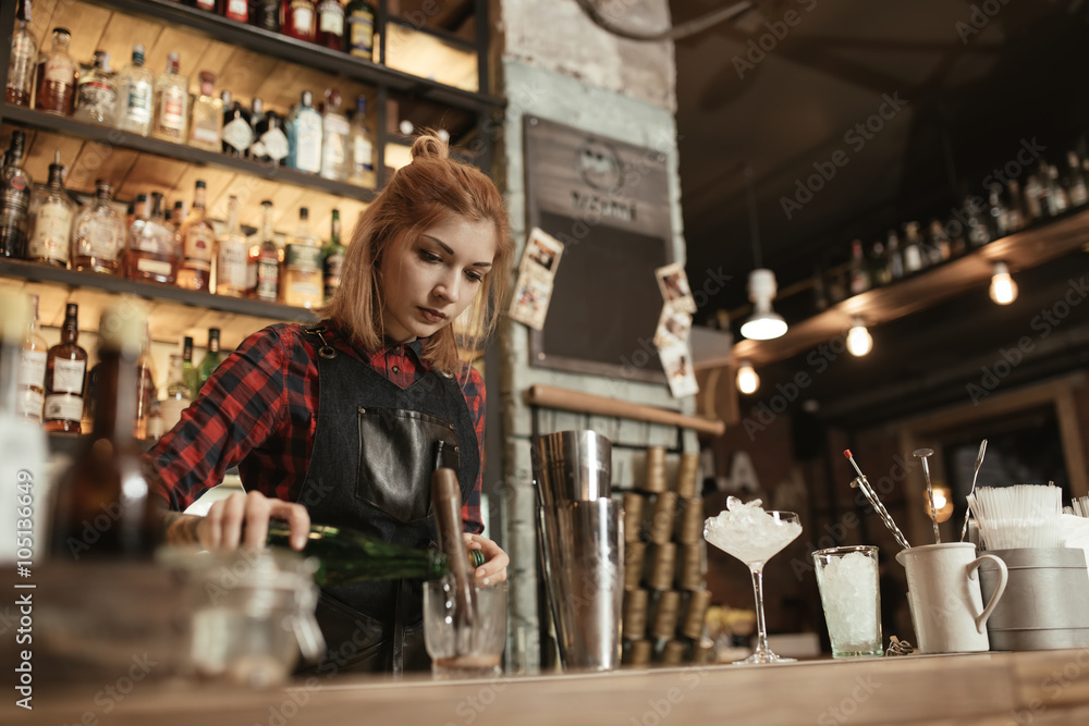 Woman bartender making an alcohol cocktail at the bar