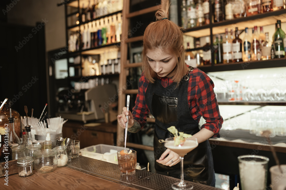 Woman bartender making an alcohol cocktail at the bar