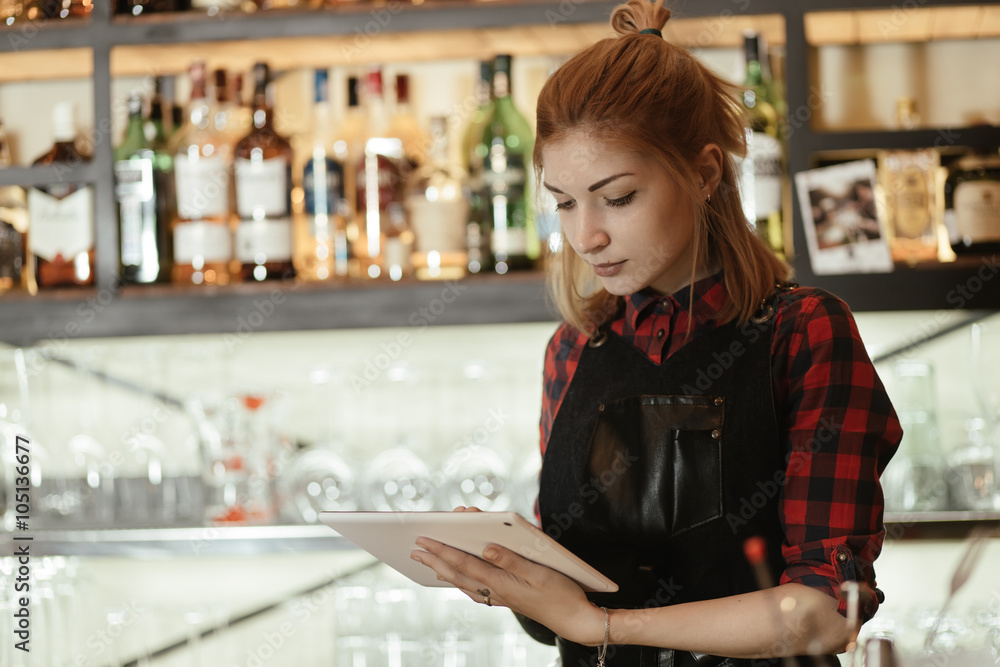 Barista woman looking at her touchscreen tablet