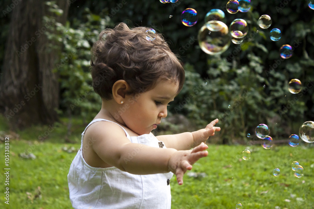 Girl playing with soap bubbles in the garden Girl playing with soap bubbles in the garden