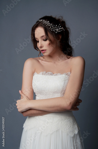 Adorable young bride with brown curly hair and pearl headpiece