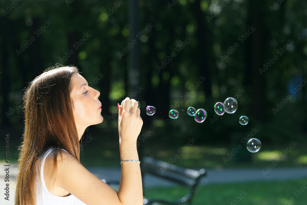 young girl blowing soap bubbles in park young girl blowing soap bubbles in park