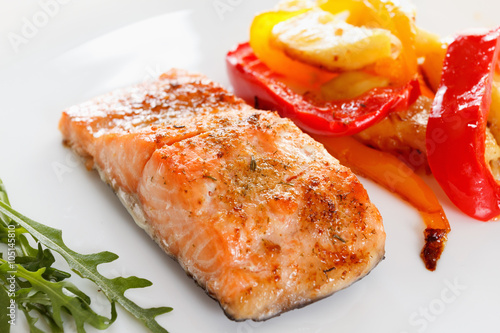 Grilled salmon fillet with vegetables, spices and arugula on a plate