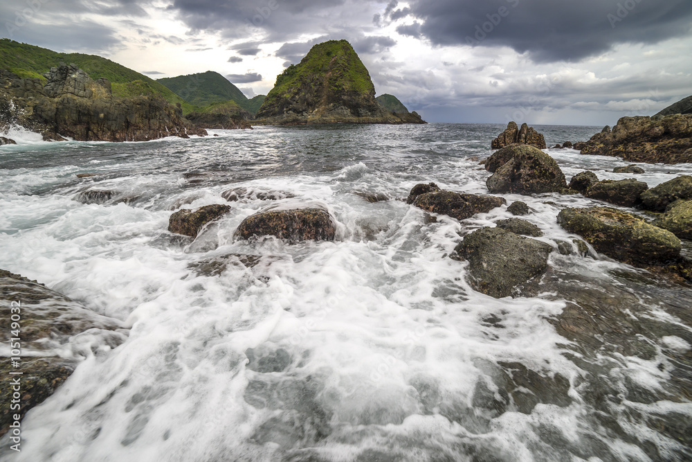 Natural rock with strong water wave and cloudy sunset background at Pantai Semeti Lombok, Indonesia.