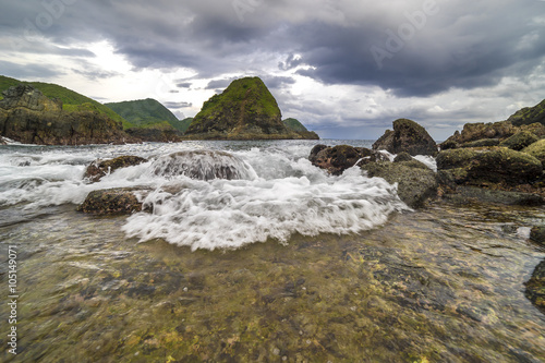 Natural rock with strong water wave and cloudy sunset background at Pantai Semeti Lombok, Indonesia. photo