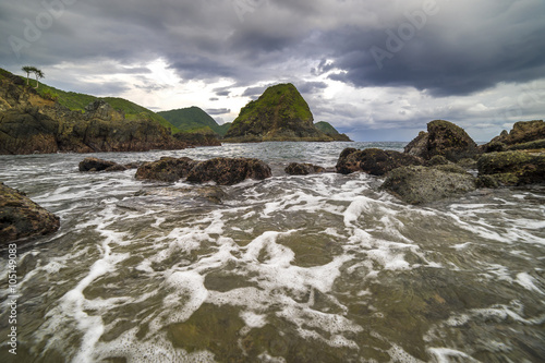 Natural rock with strong water wave and cloudy sunset background at Pantai Semeti Lombok, Indonesia.
