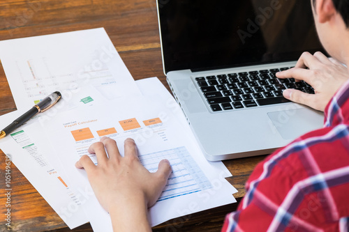 business man analysis data from paper sheet on wood table