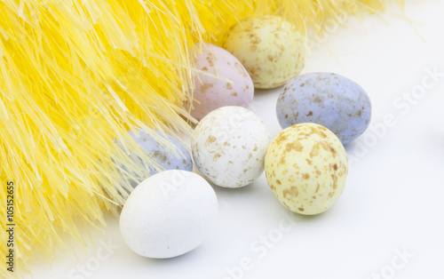 Easter eggs and yellow feathers on white background