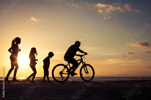 Father and children playing on the beach at the sunset time.