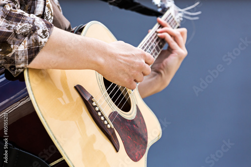 woman's hands playing acoustic guitar closeup