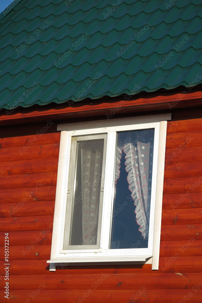 Fototapeta premium Plastic window of a modern summer cottage with the green tiled roof