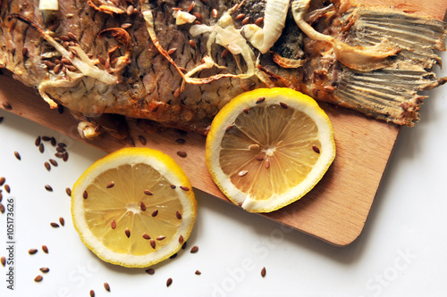 Grilled carp with lemon slices on a wooden board