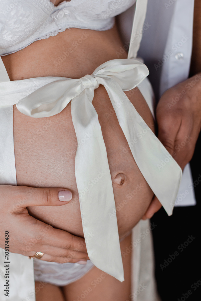 Fototapeta premium pregnant woman in white lingerie with her husband holding belly