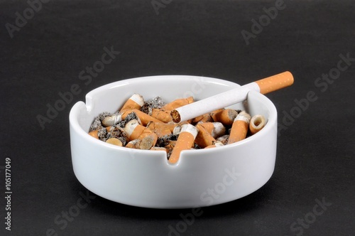 White ceramic ashtray full of smokes cigarettes