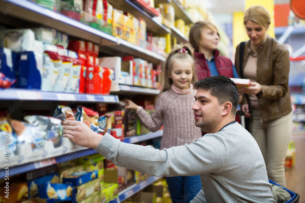 Parents with two kids choosing groats in food store