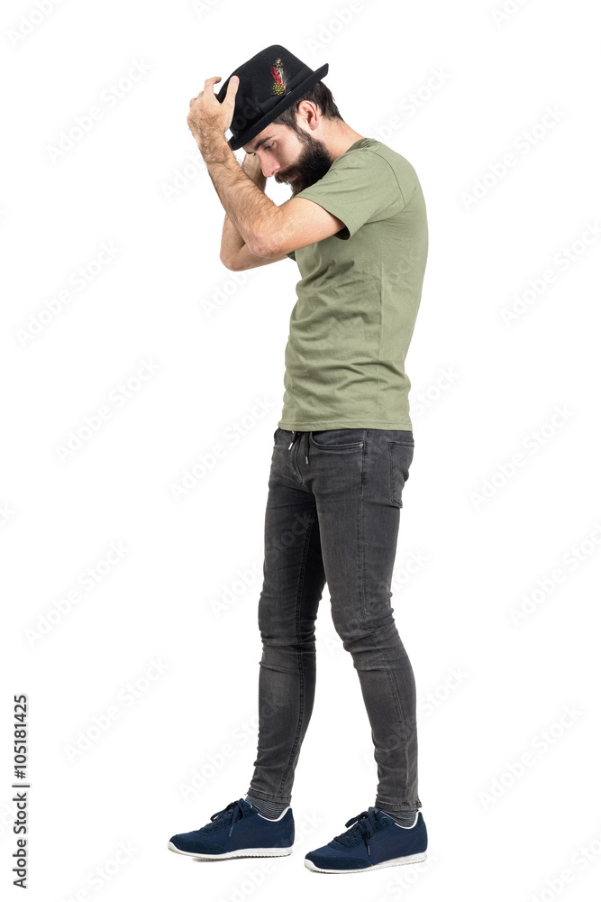 Bearded hipster walking and putting black hat with feather. Side view. Full body length portrait isolated over white studio background. Bearded hipster walking and putting black hat with feather. Side view. Full body length portrait isolated over white studio background.