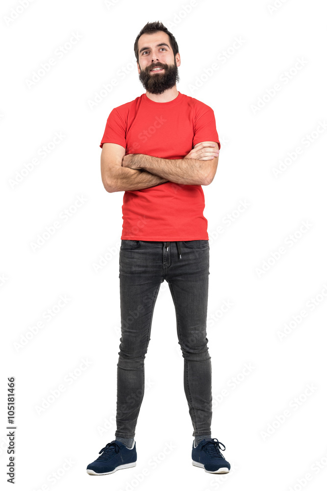 Hipster in red t-shirt with crossed arms smiling looking up. Full body length portrait isolated over white studio background. Hipster in red t-shirt with crossed arms smiling looking up. Full body length portrait isolated over white studio background.