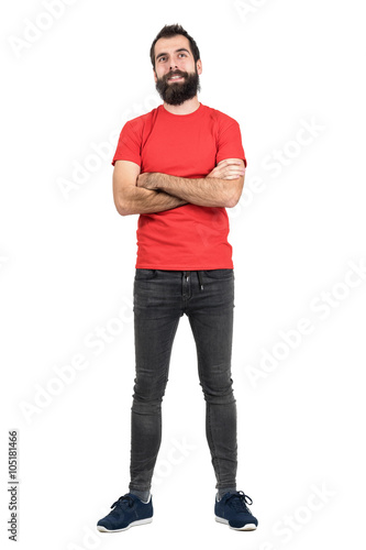 Hipster in red t-shirt with crossed arms smiling looking up. Full body length portrait isolated over white studio background.
