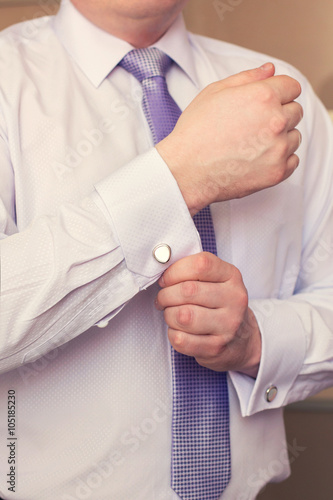 man dresses cuff links on shirt cuffs