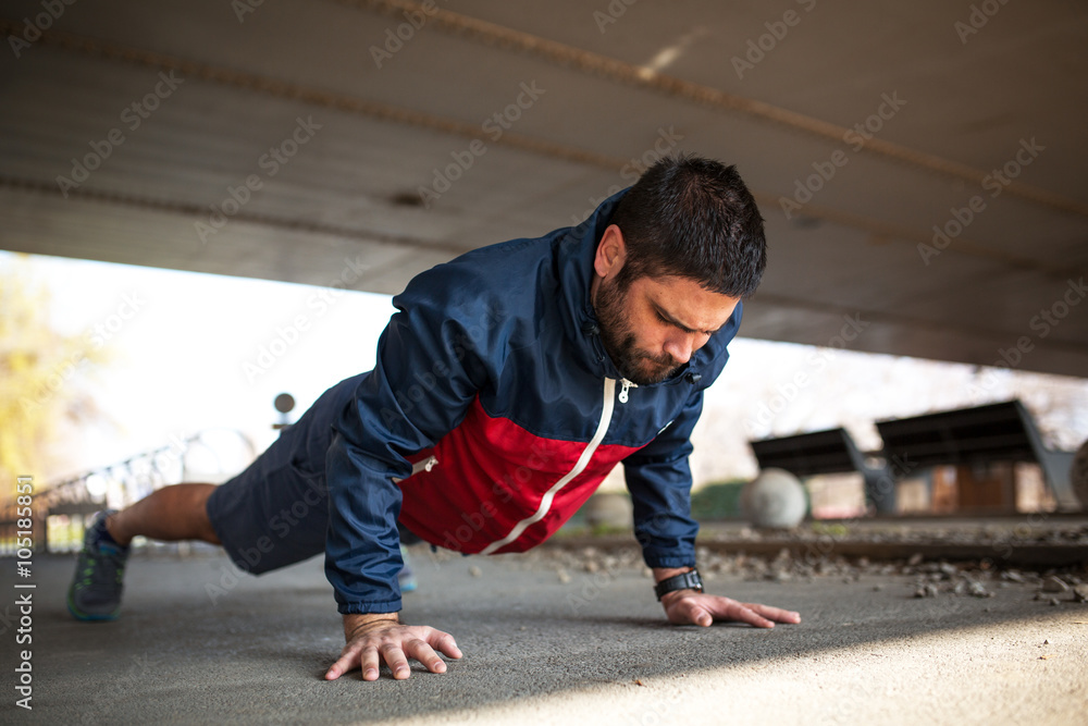 Young man doing push-ups after workout and jogging.