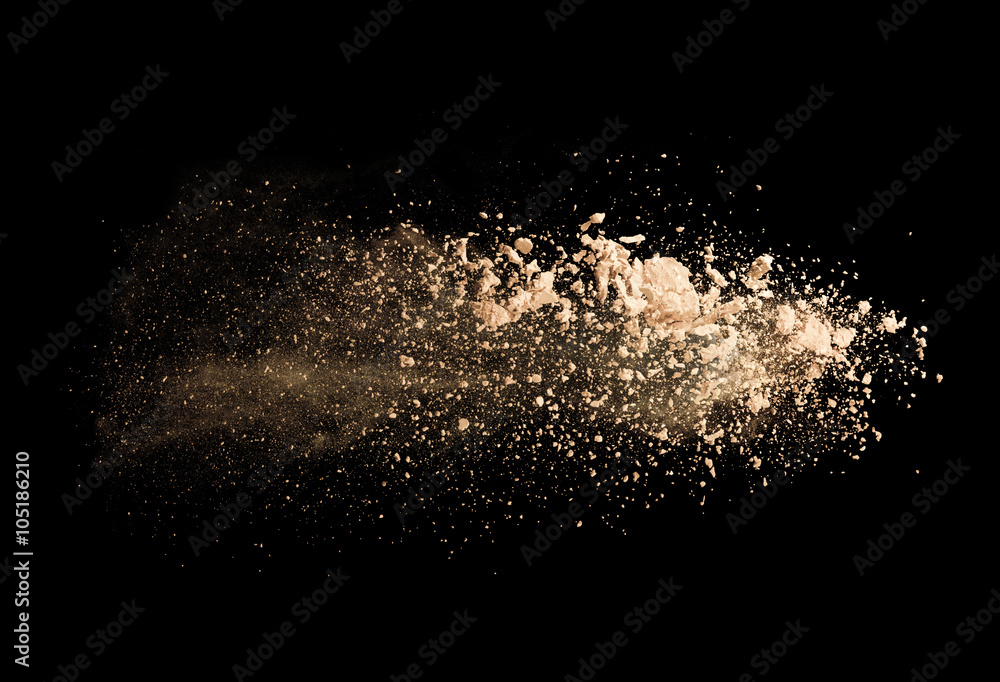 Explosion of brown powder on black background