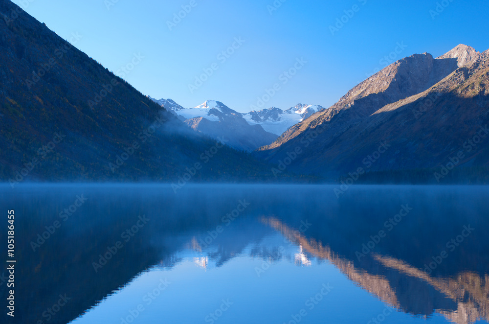 Beautiful mountain range are reflected in foggy lake