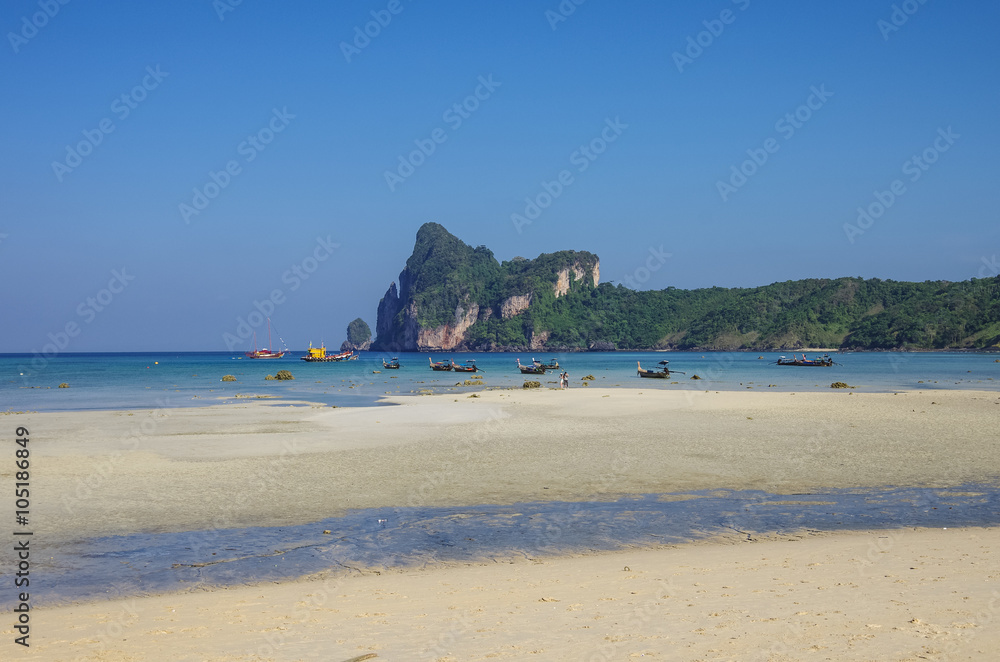 Beach of Phi Phi island in low tide with bay and longboat on background, Krabi province, Thailand