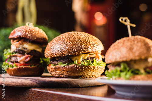 Valokuva Three juicy tasty burger on the white plate on a dark background