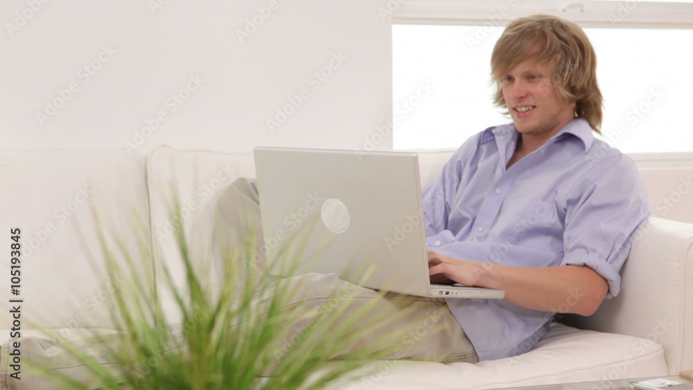Young man sitting on couch with laptop computer Young man sitting on couch with laptop computer