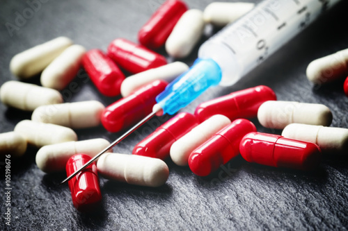 Red and white tablets in capsules, syringe for injection, dark b