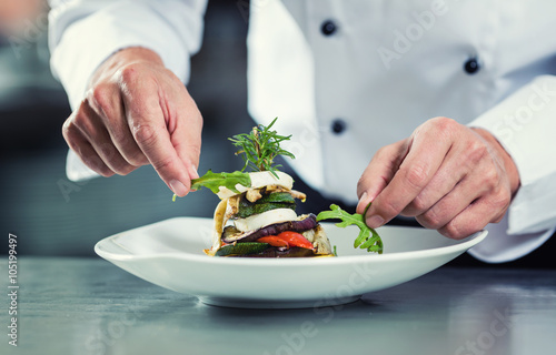 Chef in Restaurant garnishing vegetable dish photo