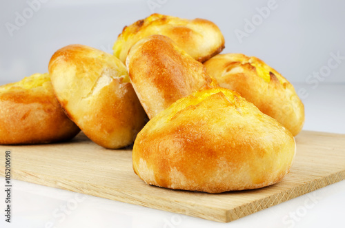 Several freshly baked buns on an oak board