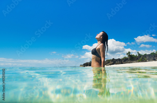 Young happy woman in black bikini enjoys sunny day on the sea. Tropical vacation