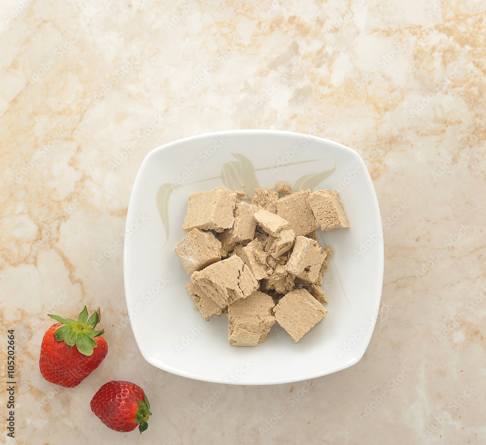 Oriental sweets - halva in a plate with strawberry on marble bac Oriental sweets - halva in a plate with strawberry on marble bac