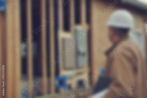 Blurred Construction Worker Inspecting Home Construction Site wi © bbourdages