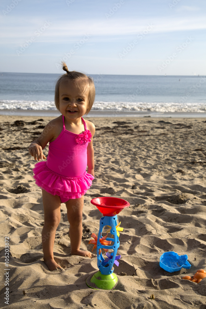 Cute gril toddler on the beach playing in sand with toys Cute gril toddler on the beach playing in sand with toys