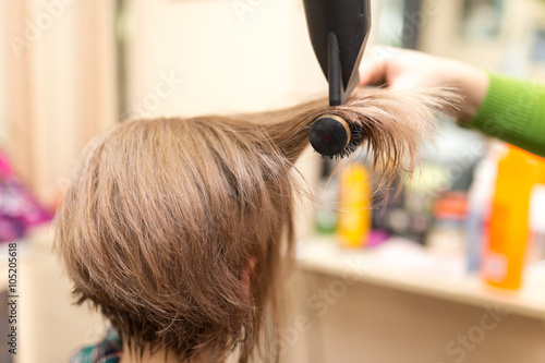 Hairdresser dries the hair dryer blond hair